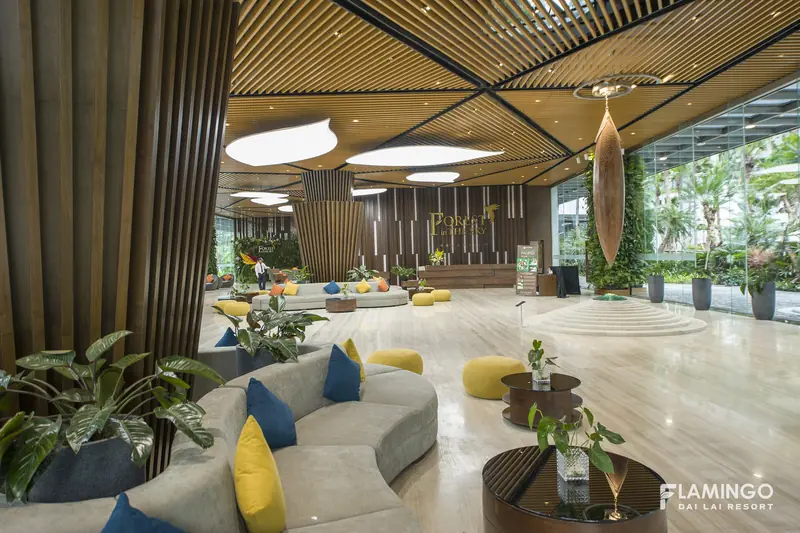Sảnh đón khách tòa Forest in the Sky với sofa xám, gối vàng và trần gỗ, cửa kính nhìn ra cây xanh