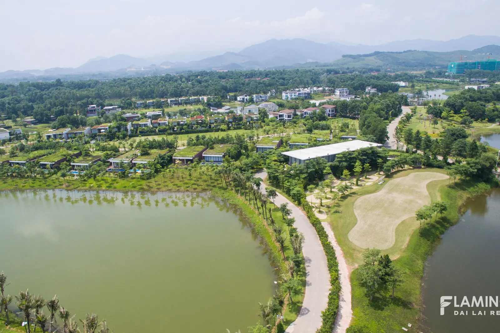 Hồ nước, đồi cỏ và các cụm biệt thự xanh trong Flamingo Đại Lải nhìn từ trên cao, xa xa là dãy Tam Đảo