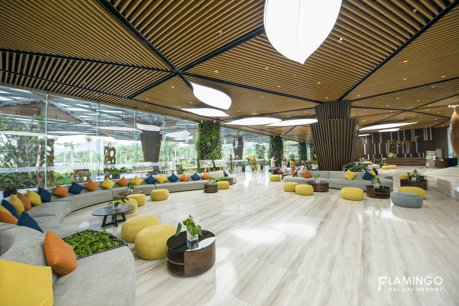Sảnh chờ rộng trong tòa Forest in the Sky với sofa cong, ghế đôn màu và vách kính nhìn ra cây xanh