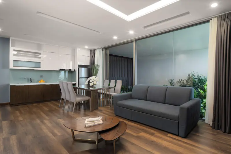 Phòng khách và bếp căn Executive Sky Residence 2 phòng ngủ, sofa xám và vách kính phủ cây