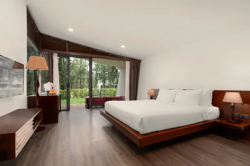 Phòng ngủ Hilltop Villa với giường đôi gỗ, cửa kính mở ra bãi cỏ
