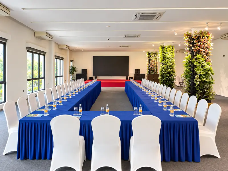 Opera House xếp bàn chữ U phủ khăn xanh, màn LED cuối phòng, cửa kính nhìn ra cây xanh