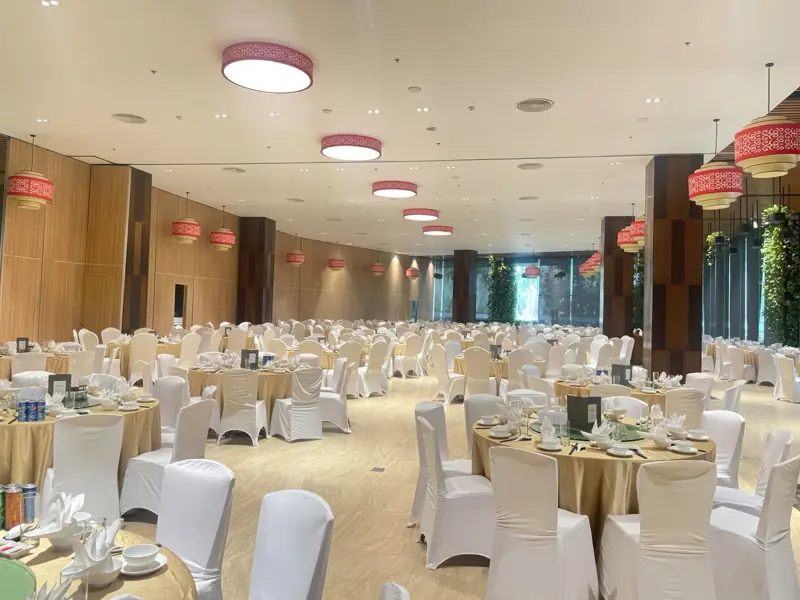 Symphony Hall bày tiệc bàn tròn cho đoàn đông, cột gỗ và vách cây xanh hai bên