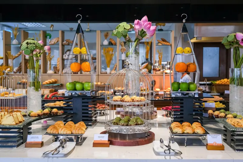 Quầy buffet sáng bày bánh sừng bò, bánh ngọt và trái cây ở Flamingo Đại Lải