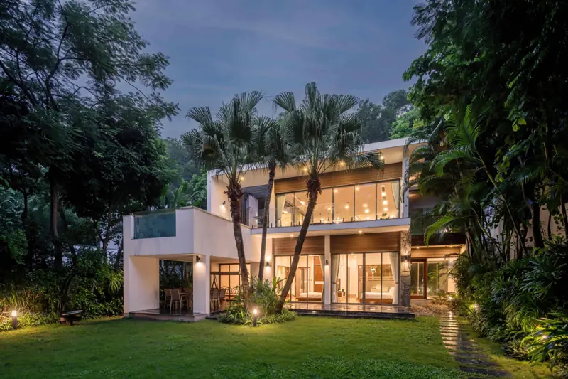 Charm Villa hai tầng sáng đèn lúc chập tối, trước nhà là sân cỏ và hàng cọ