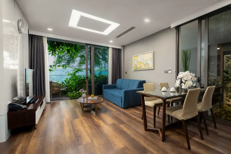 Phòng khách Executive Sky Residence 1 phòng ngủ: sofa, bàn ăn và cửa kính nhìn ra cây xanh