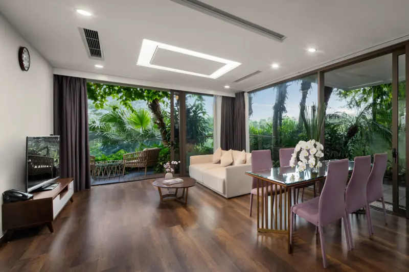 Phòng khách Executive Sky Residence 3 phòng ngủ: bàn ăn ghế tím, sofa và vách kính phủ cây xanh