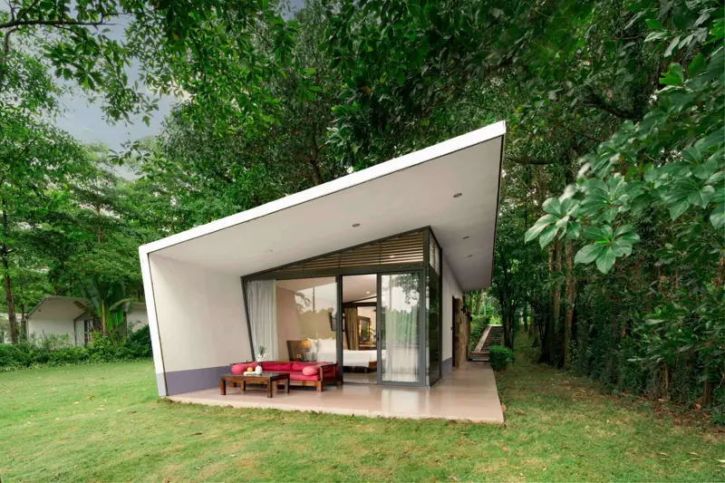 Forest Villa một tầng mái trắng, vách kính, trước nhà là sân cỏ và rừng cây
