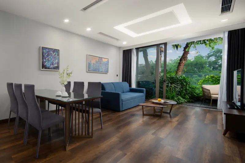 Phòng khách Premier Sky Residence 2 phòng ngủ: bàn ăn 6 ghế, sofa và cửa kính ra ban công cây xanh