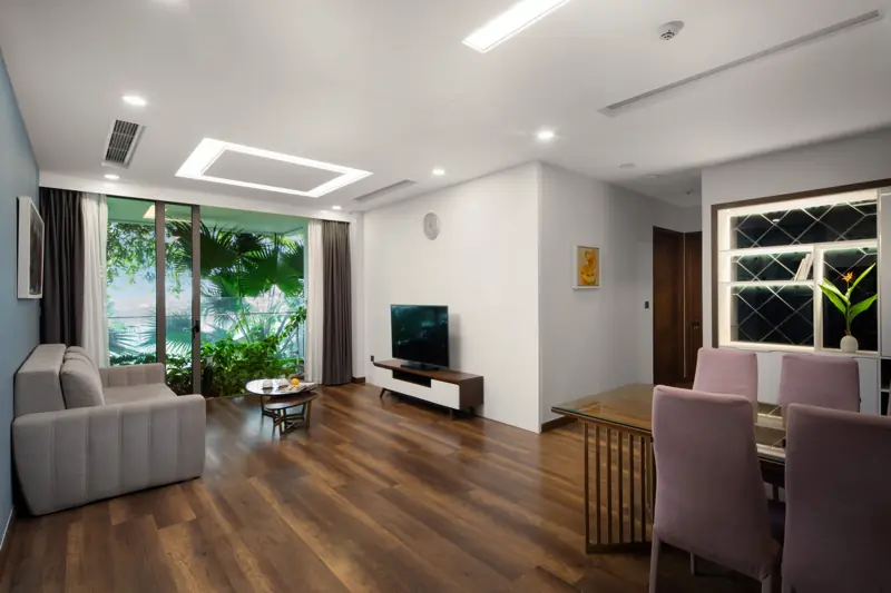 Phòng khách Premier Sky Residence 3 phòng ngủ: sofa, bàn ăn và cửa kính nhìn ra cây xanh