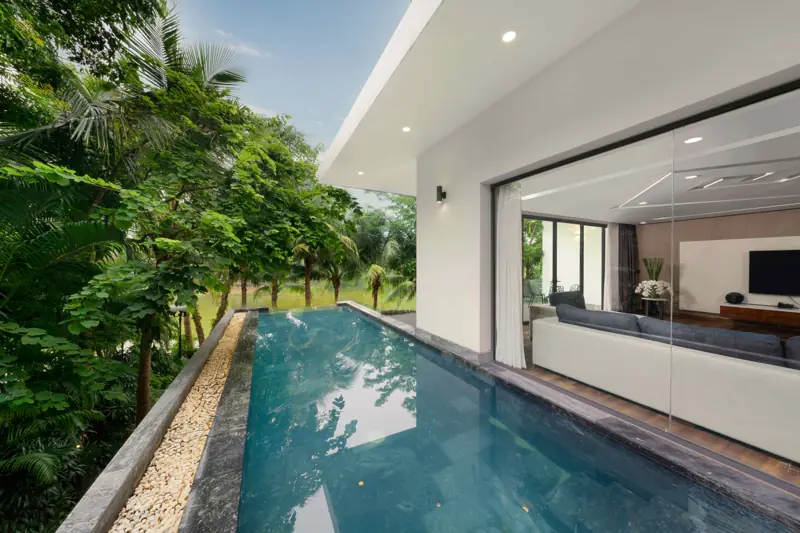 Bể bơi dài dọc hiên một căn Luxury Skylake Villa, bên vách kính phòng khách